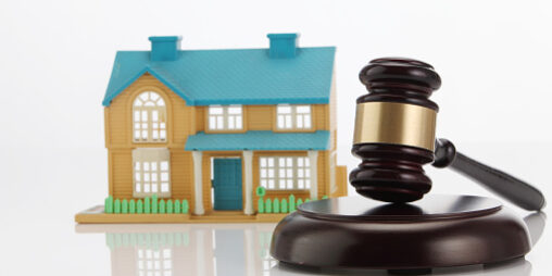 Close-Up Of Gavel By Model House On White Background