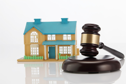 Close-Up Of Gavel By Model House On White Background
