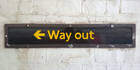 “Way out” sign on brick wall in London subway