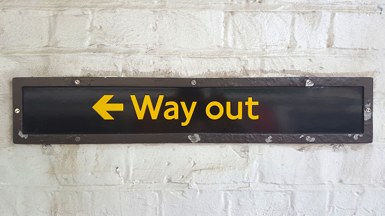 “Way out” sign on brick wall in London subway