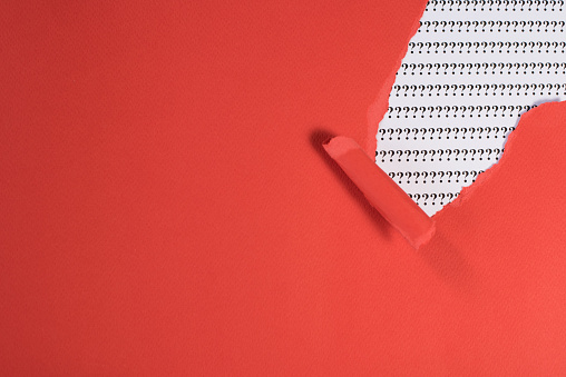 Red Paper Teared Revealing Question Mark On White Paper.